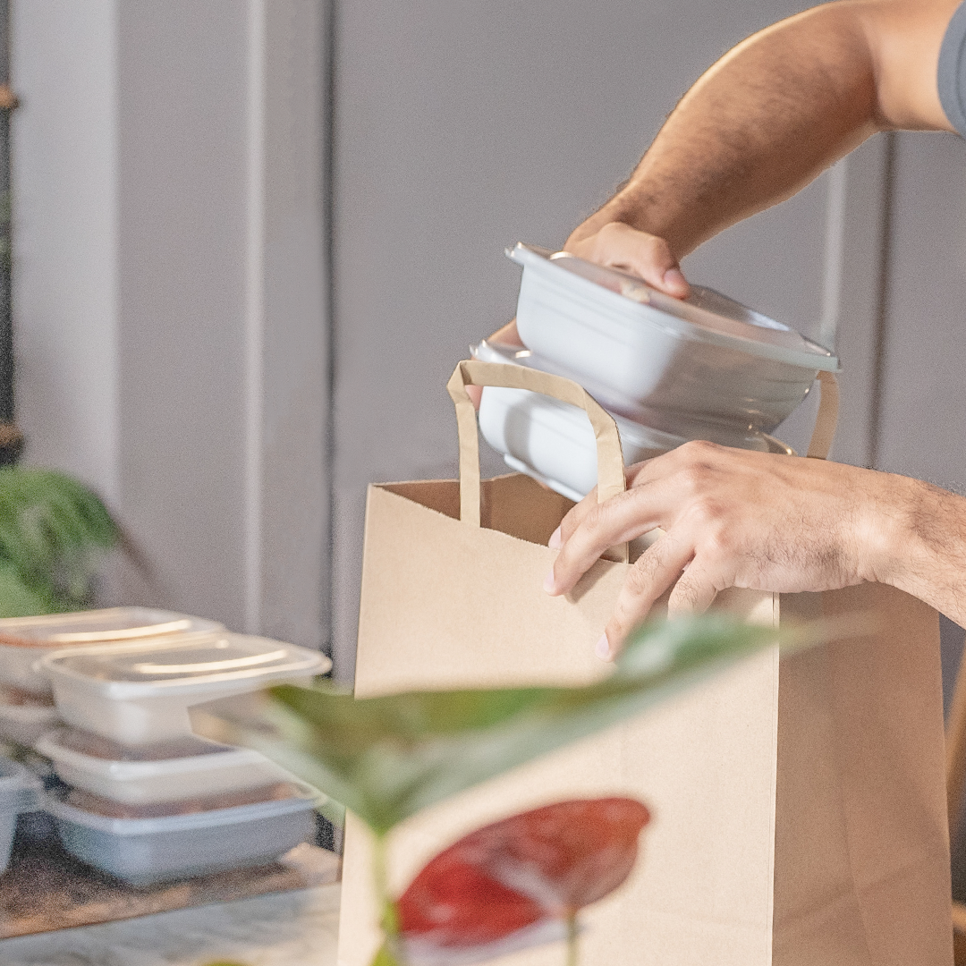 man putting groceries into a paper bag
