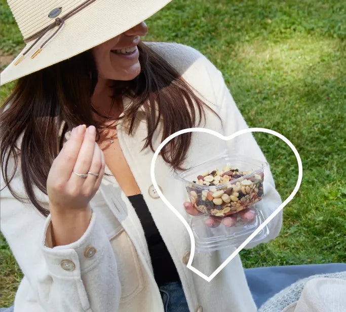Happy woman enjoying nuts and a picnic.