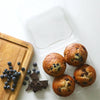 compostable bioplastic baked good 4 pack with 4 large muffins next to chocolate and blueberries on cutting board
