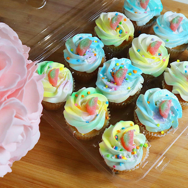 Biodegradable 12-pack 3.25" Cupcake & Muffin Package made of clear, compostable plastic beside an assortment of tulips and cupcakes