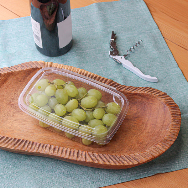 Vented plant-based container with grapes being served  on a wooden platter with some wine in the side