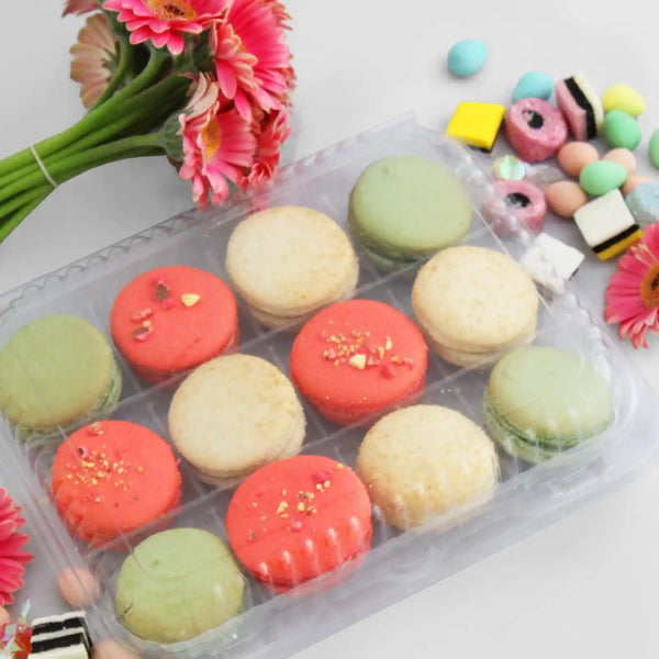  12 pack of macarons amongst flowers and licorice allsorts.