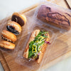 48 oz compostable food packaging with donuts, a sandwich, and a small loaf of bread