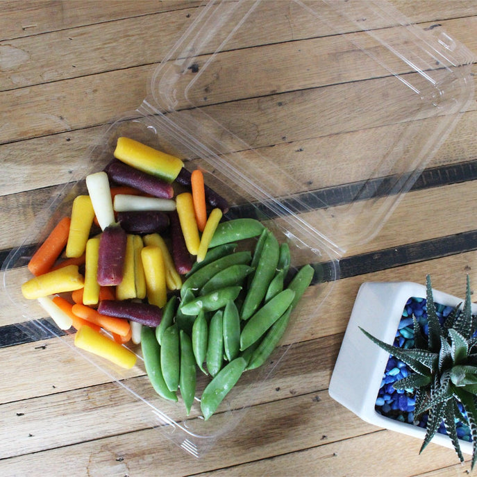 1.75” food tray made of clear, compostable bioplastic containing rainbow baby carrots and snap peas.