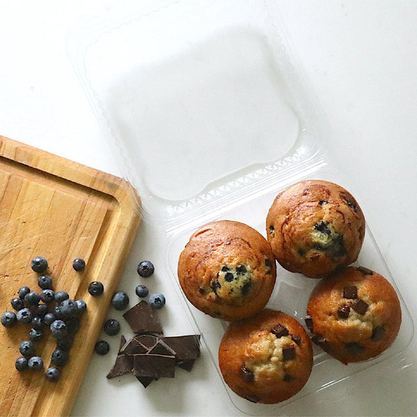 compostable bioplastic baked good 4 pack with 4 large muffins next to chocolate and blueberries on cutting board